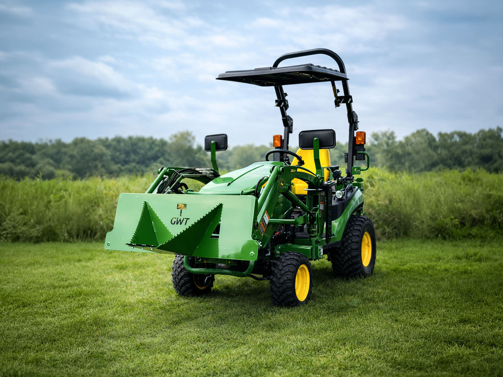 John Deere 1025R in a grassy field with a stump bucket