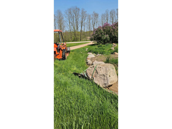 Yard Glider Hauling Boulder Behind Tractor