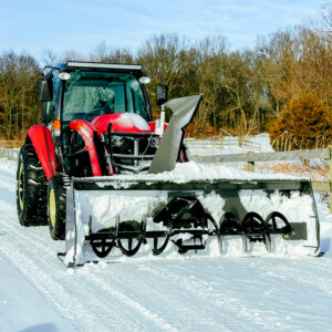 Snow blower mounted to the loader of a red Yanmar tractor